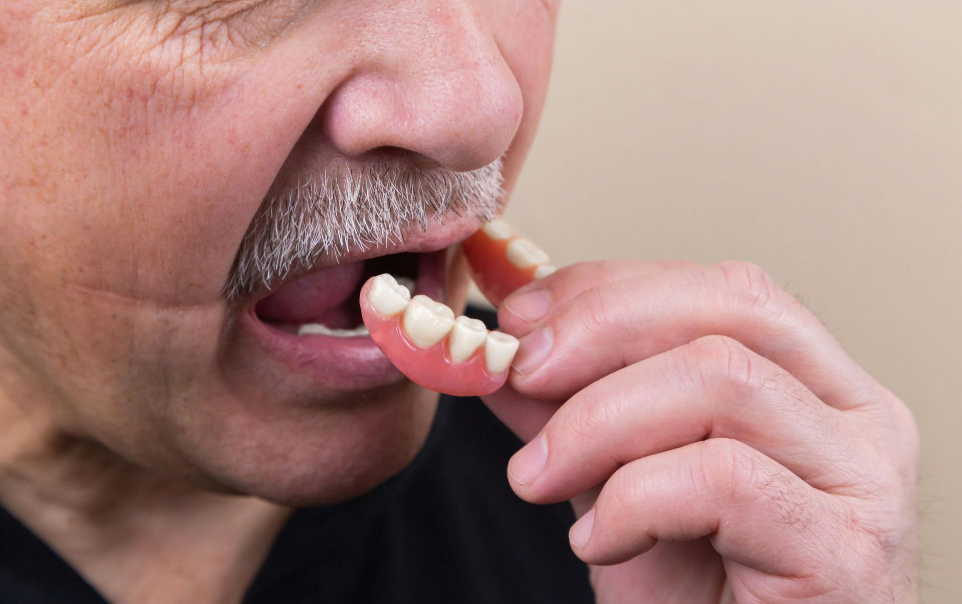 Man holding and about to insert dentures into his mouth.
