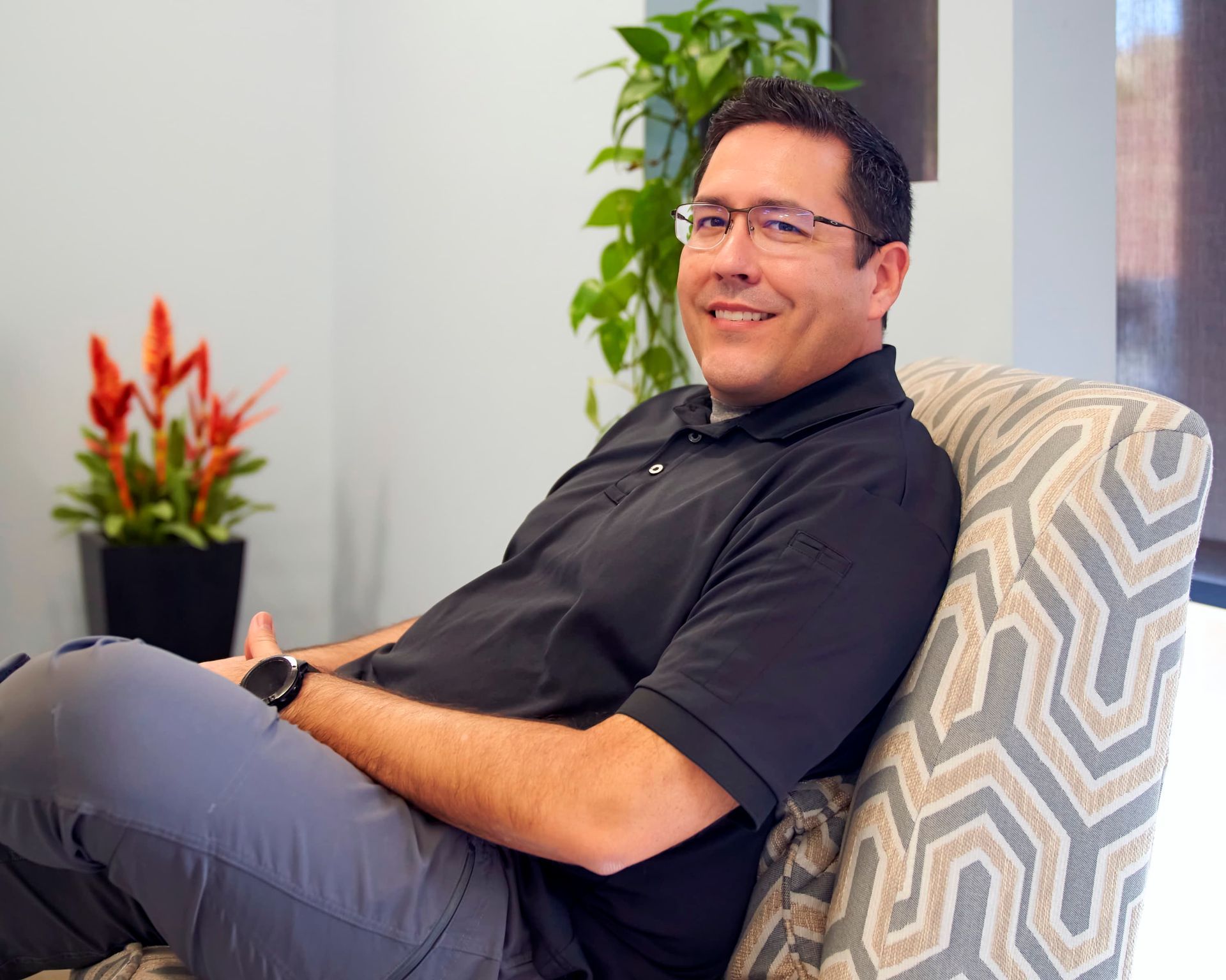 Smiling person in gray scrubs, possibly a healthcare professional.