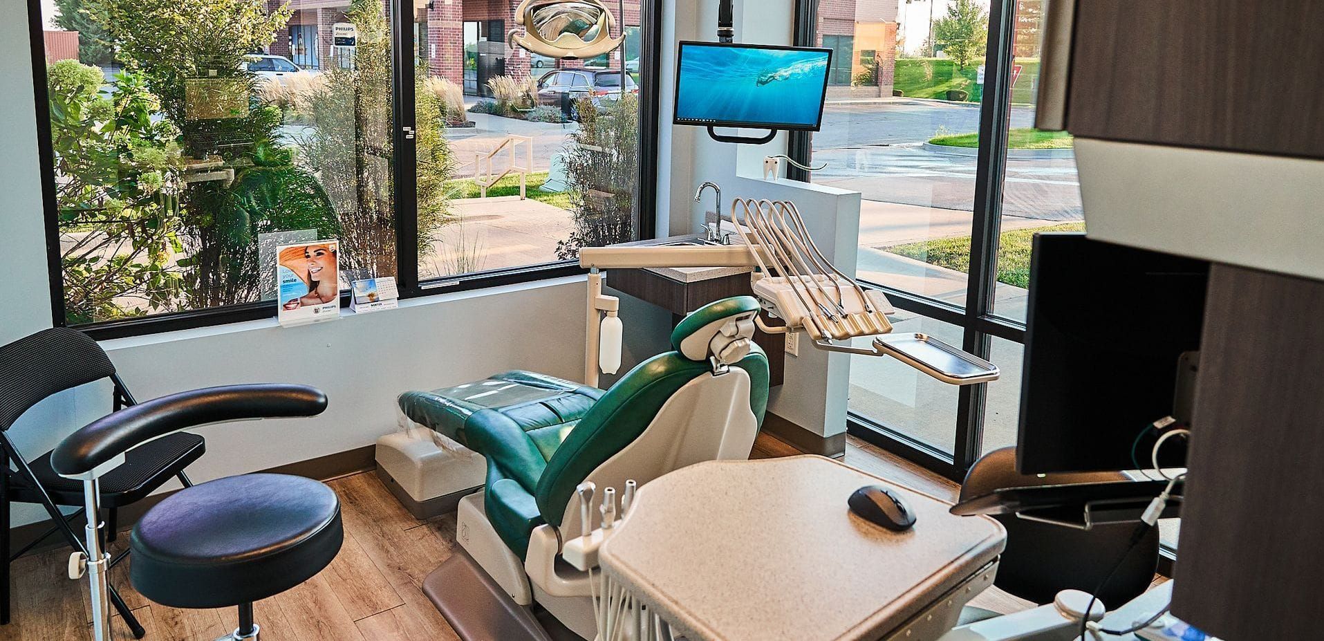 A dental office with a green dental chair and a large window.