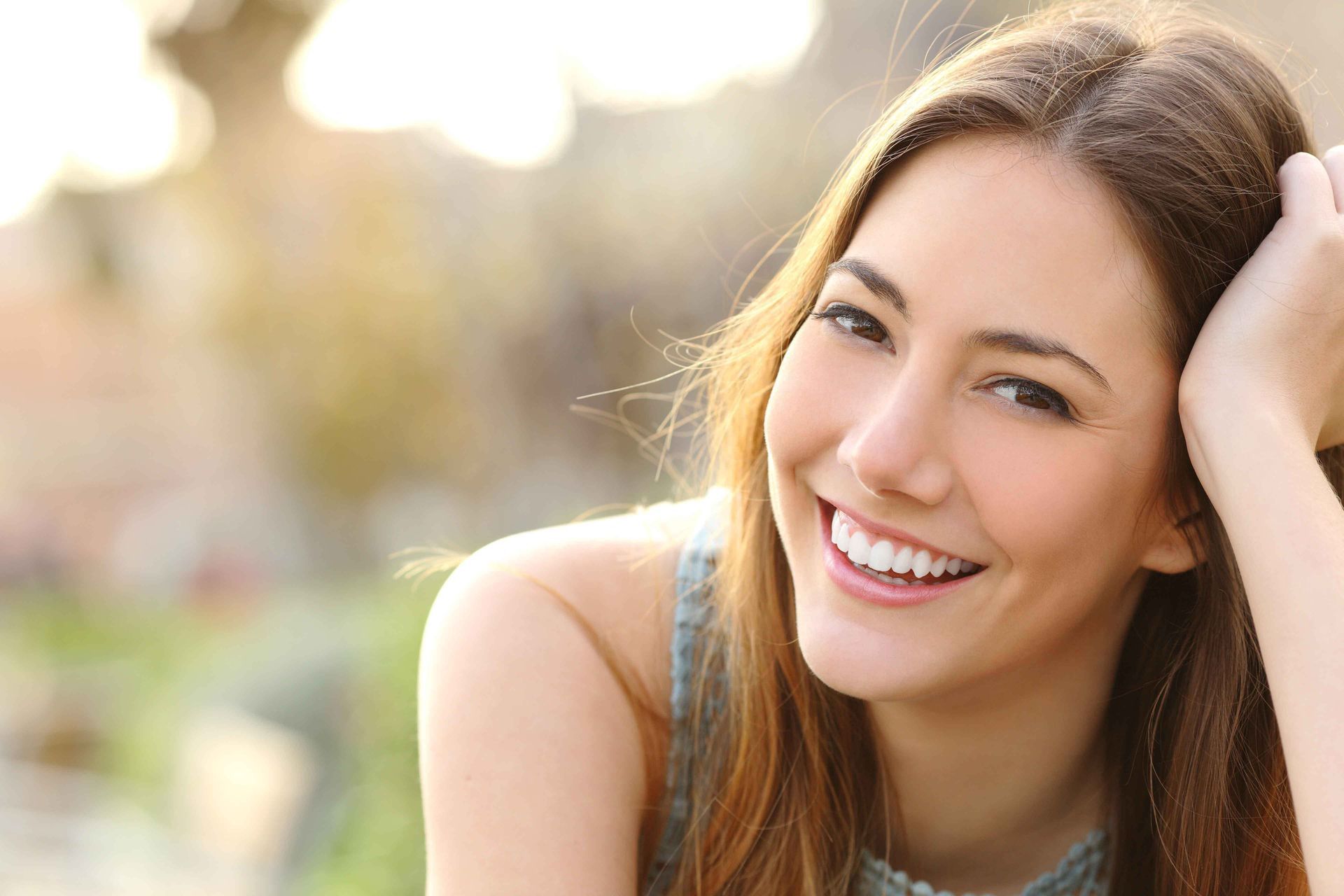 A close up of a woman smiling with her hand in her hair.