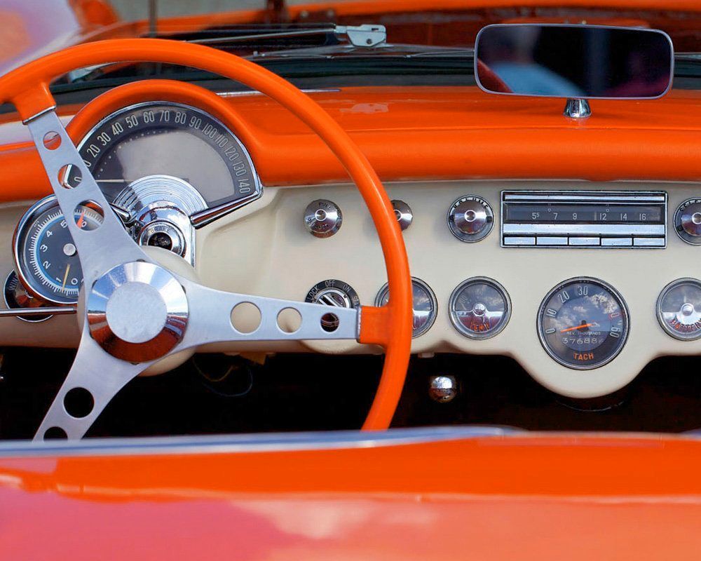 A close up of an orange car dashboard with a steering wheel