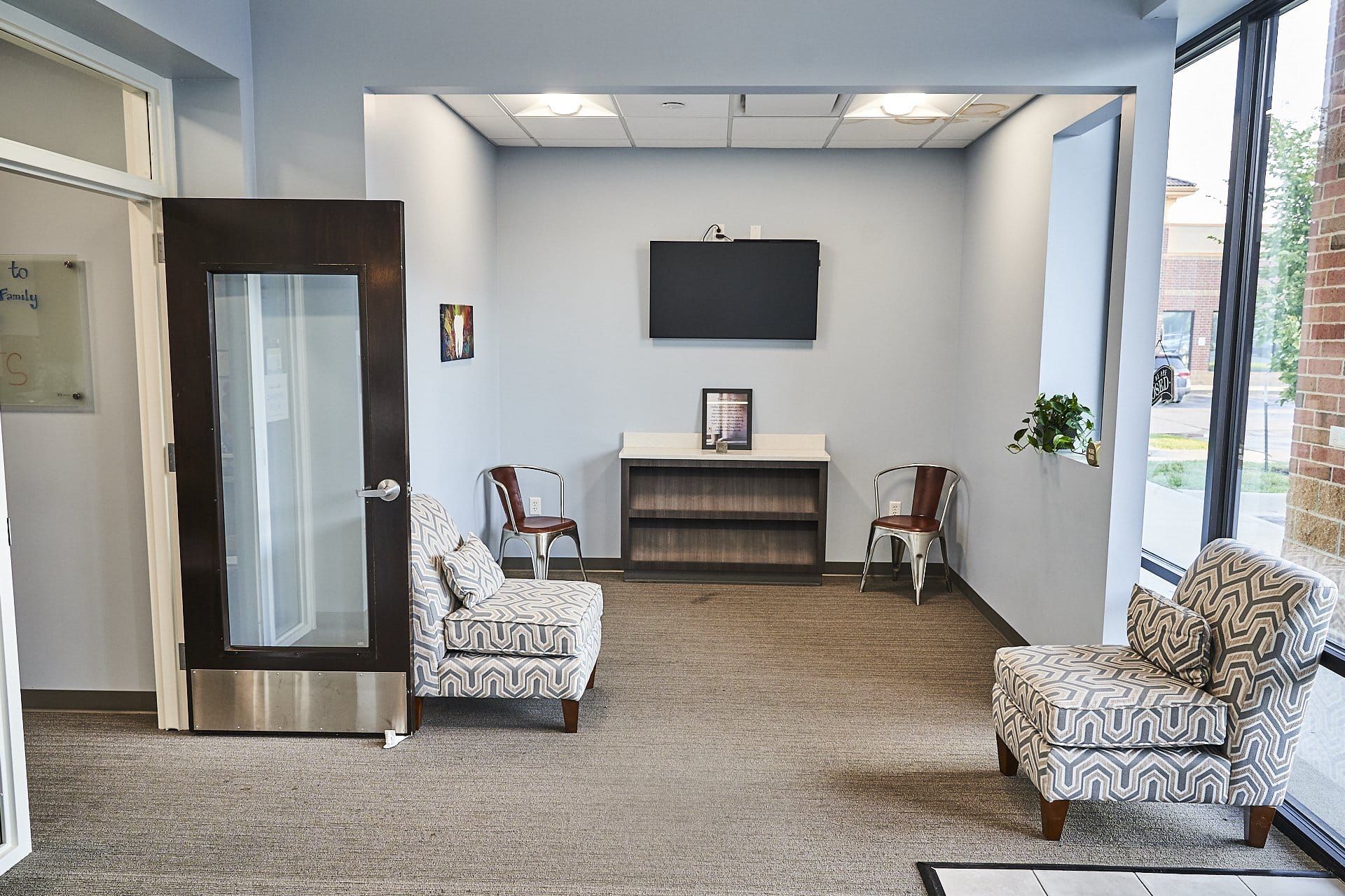 A waiting room with chairs and a tv on the wall