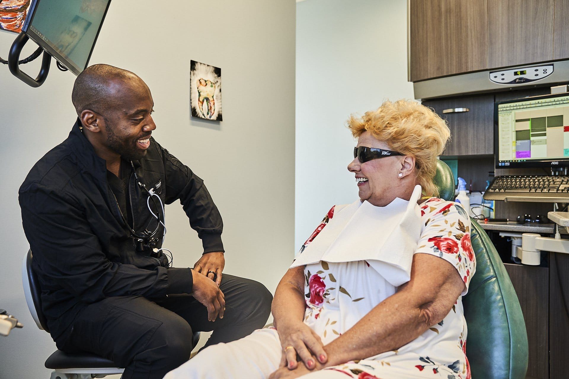 A man is talking to a woman in a dental chair.