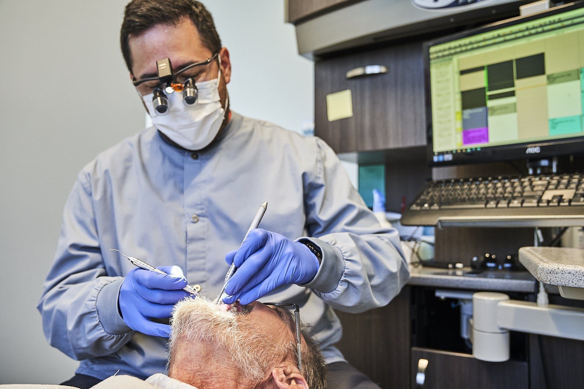 Dr. Dave is examining a patient 's teeth in a dental office.