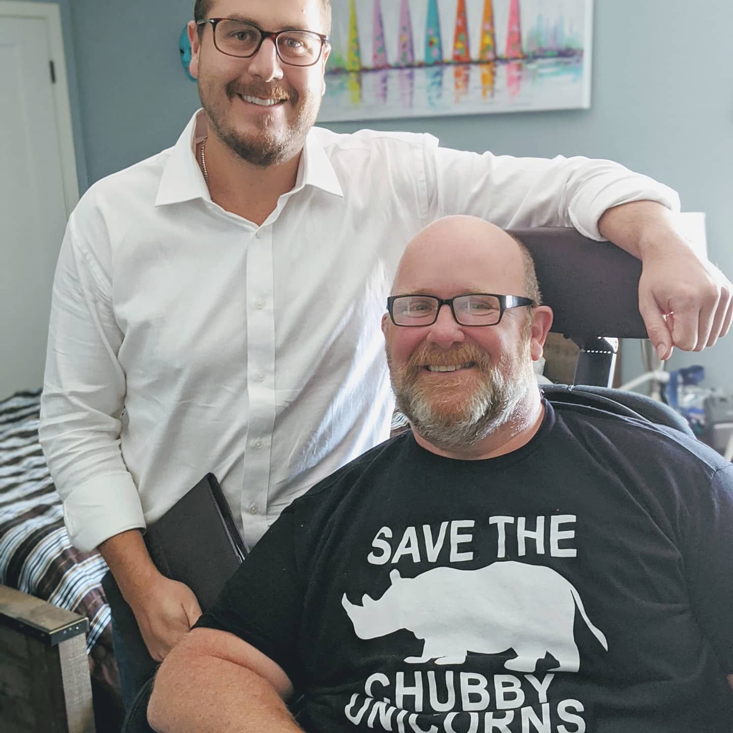 A man in a black shirt that says save the chubby unicorns