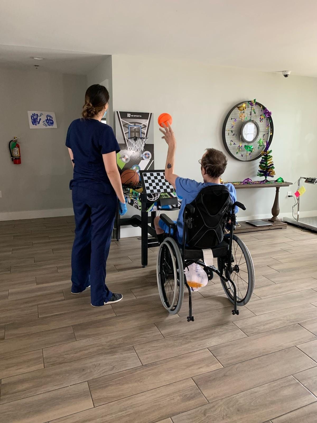 A woman is standing next to a boy in a wheelchair holding a ball.