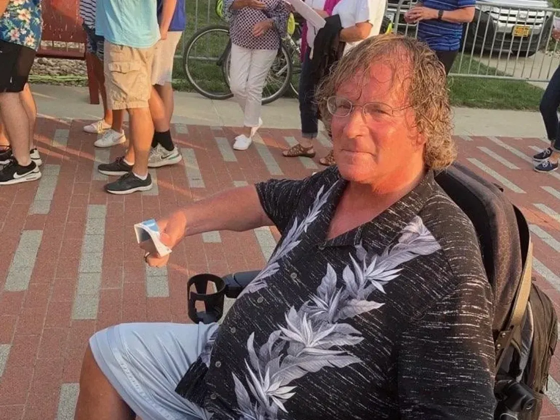 A man in a wheelchair is holding a remote control.