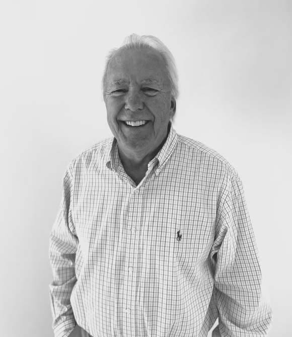 A man in a plaid shirt is smiling in a black and white photo.