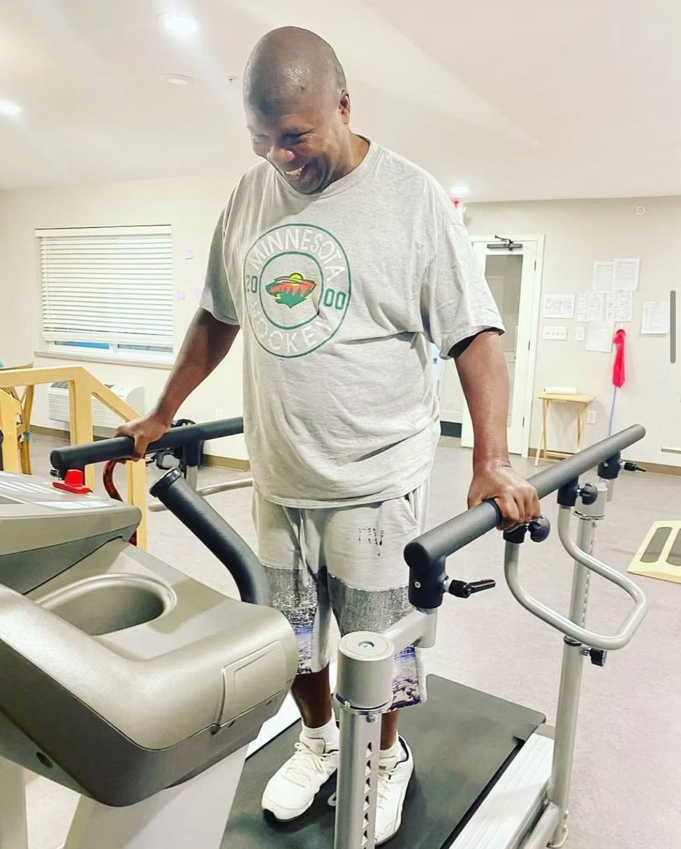 A man is standing on a treadmill in a gym.