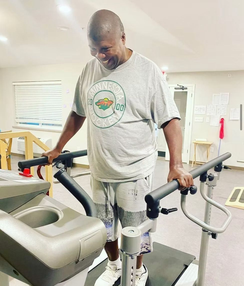 A man is standing on a treadmill in a gym.