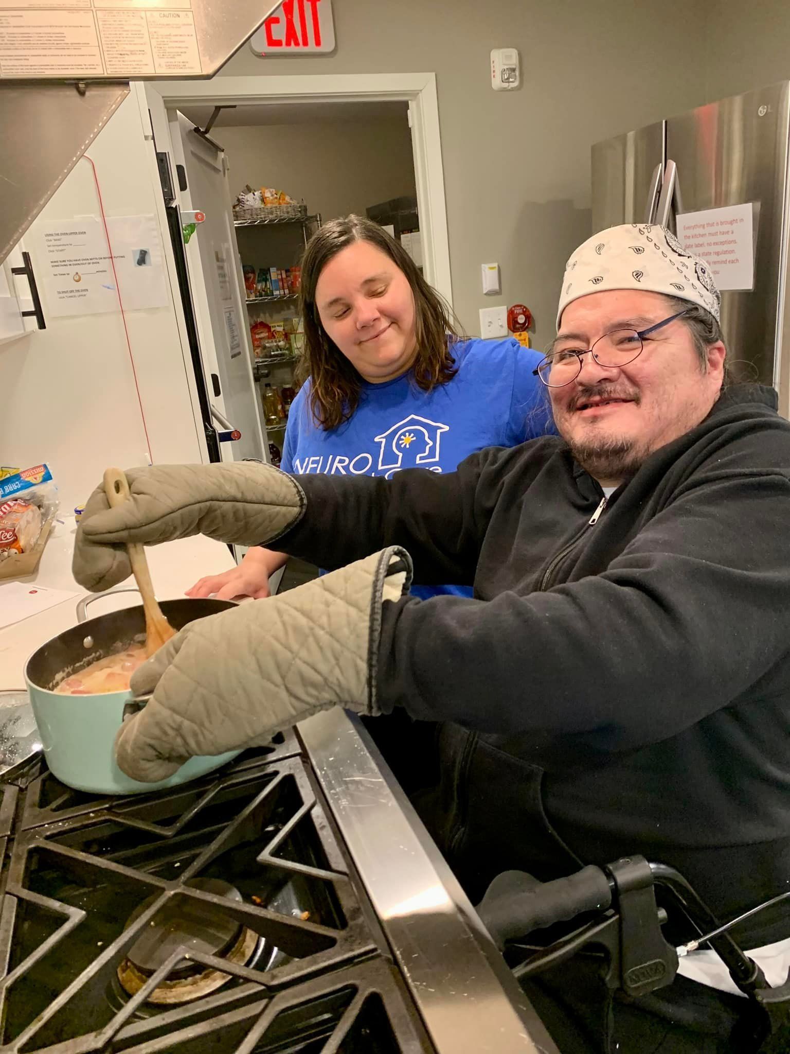 A man and a woman are cooking on a stove in a kitchen.