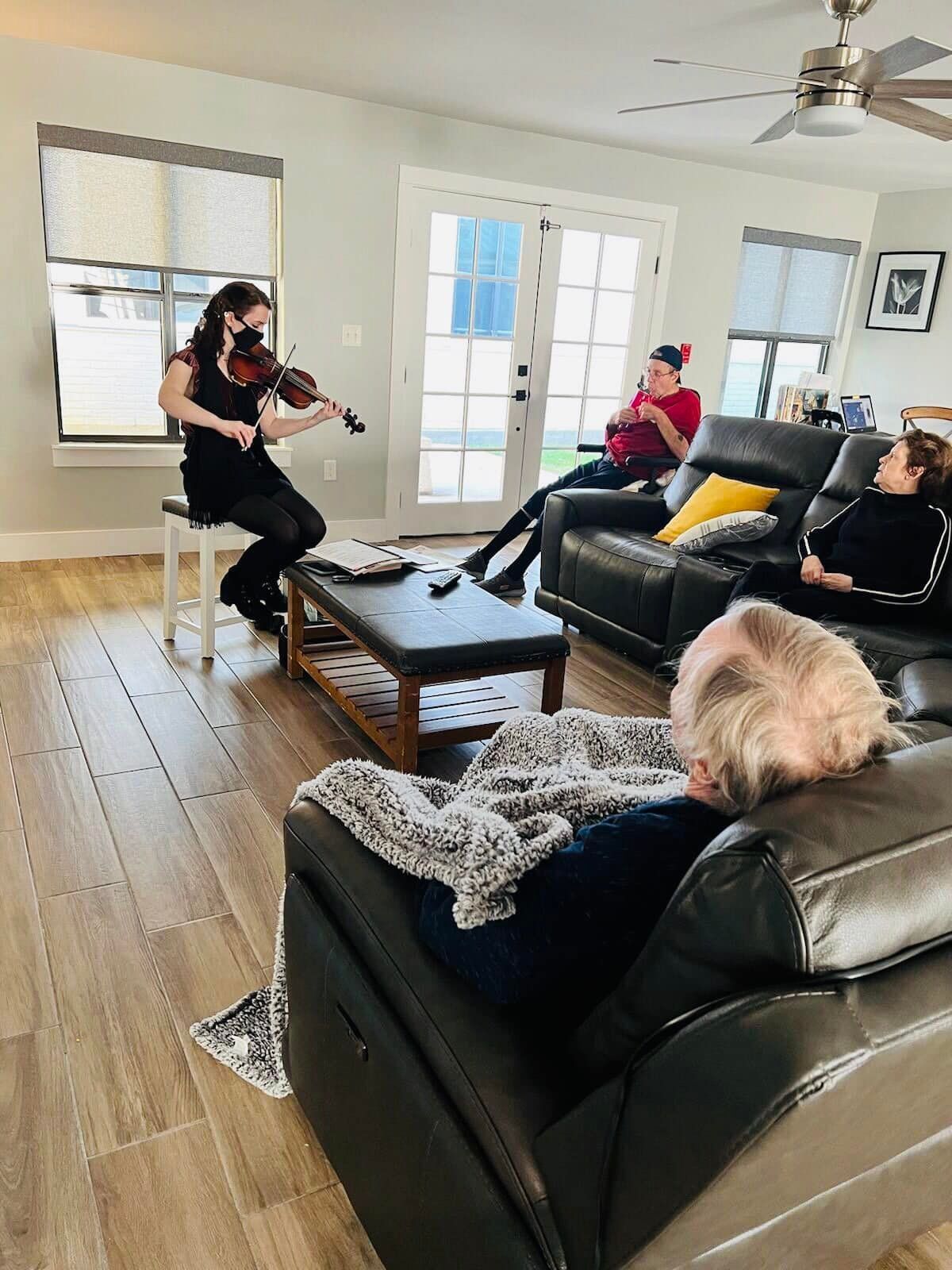 A group of people are sitting around a table with a christmas tree in the background.
