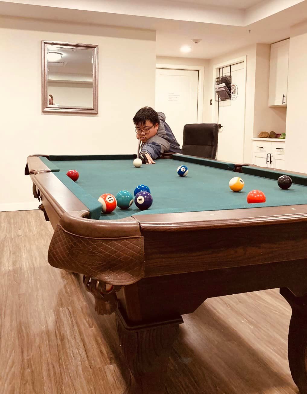 A man is playing pool in a basement.