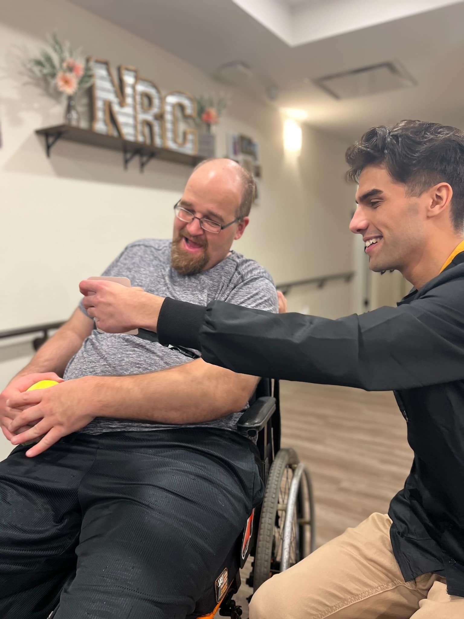 A man in a wheelchair is being helped by another man.