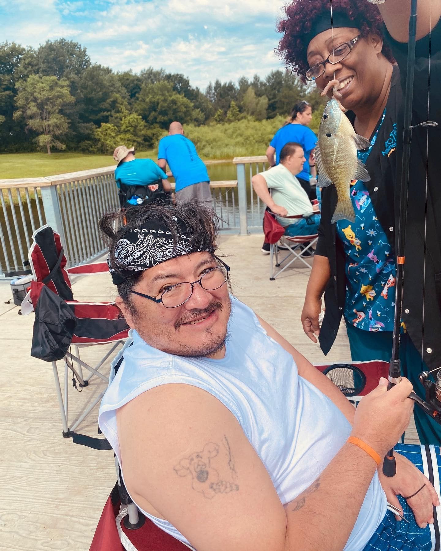 A man is holding a fishing rod next to a woman holding a fish.