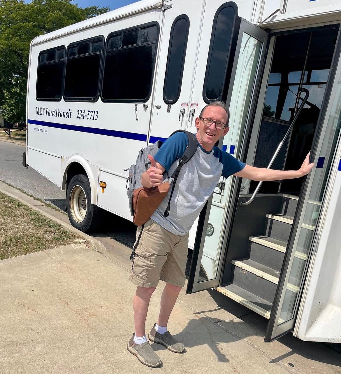 A man with a backpack is getting off a bus.