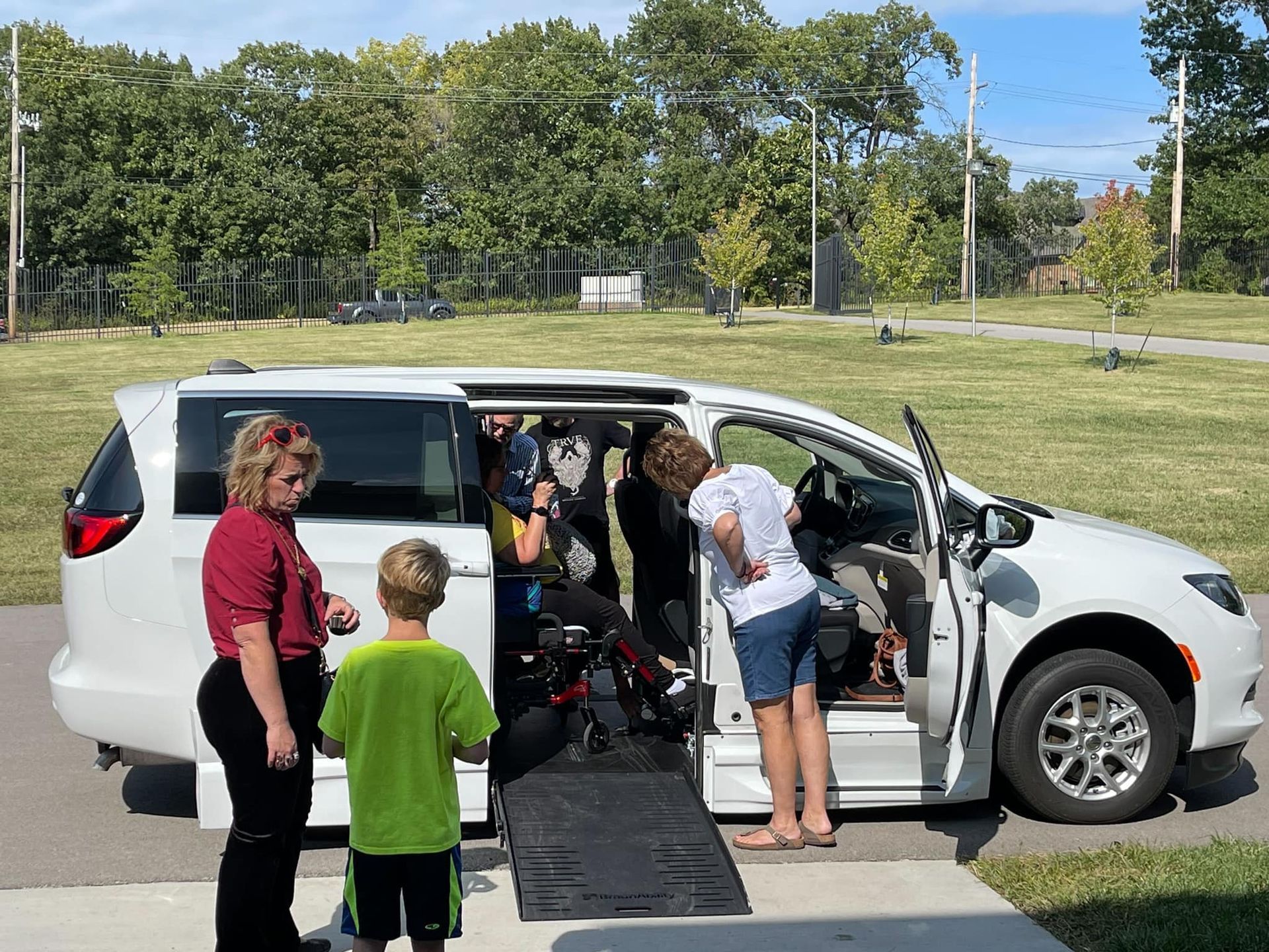 A group of people are standing next to a white van with a ramp.
