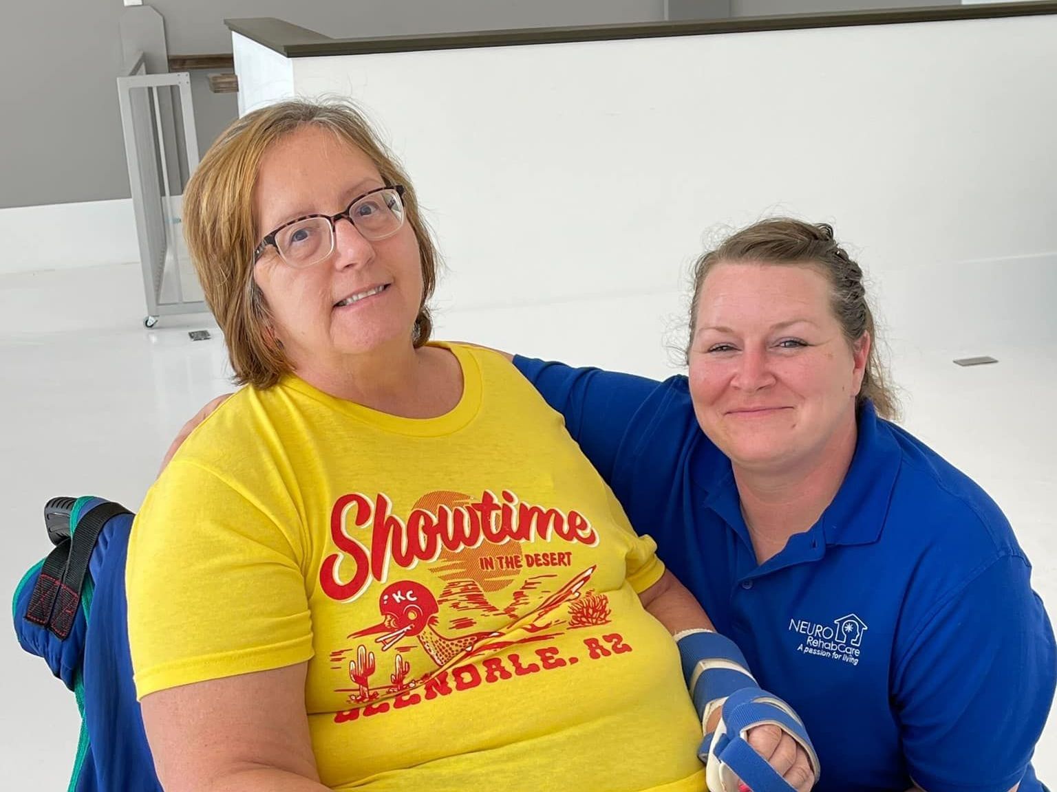 Two women are posing for a picture and one is wearing a yellow shirt that says showtime