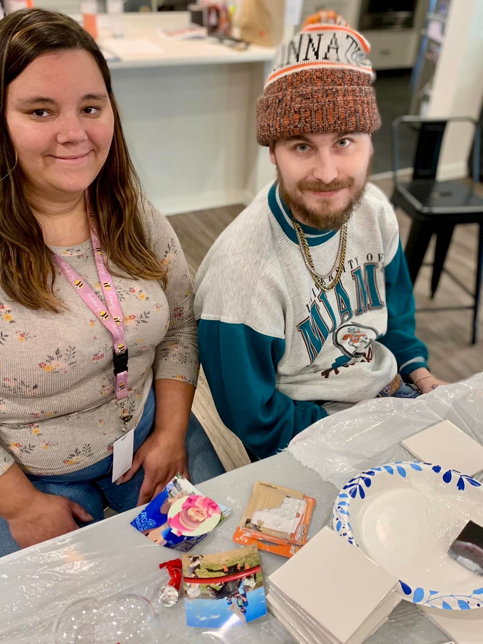 A man and a woman are sitting at a table with plates and napkins.