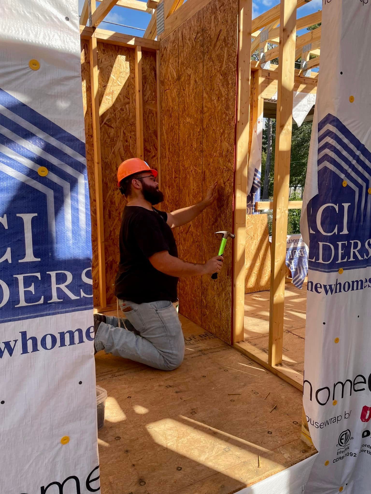 A man is kneeling down in front of a building under construction.