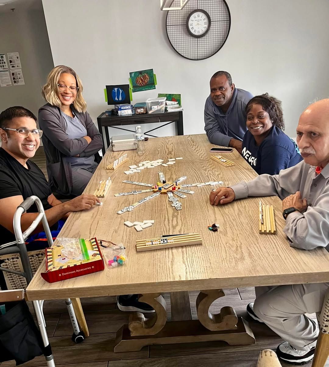 A group of people are sitting at a table with a clock on the wall.