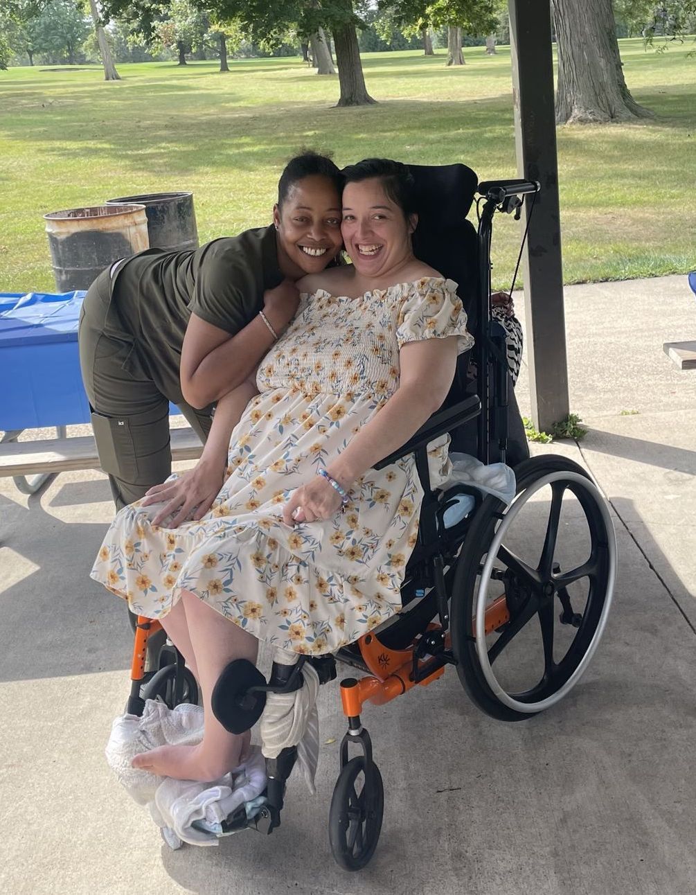 A woman in a wheelchair is being hugged by another woman
