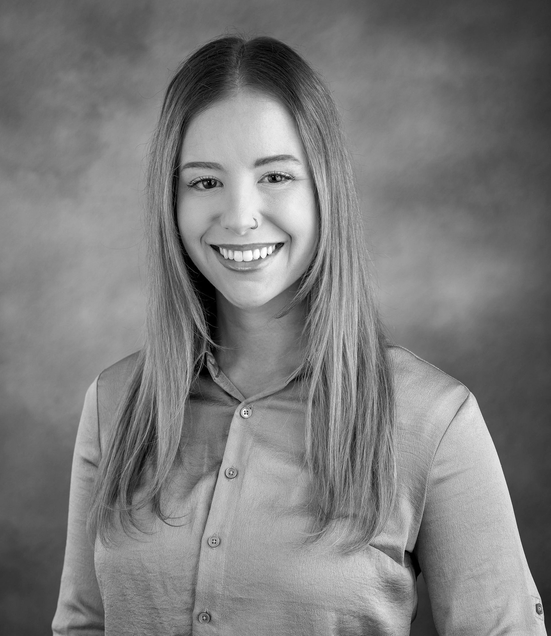 A woman with long hair is smiling in a black and white photo.