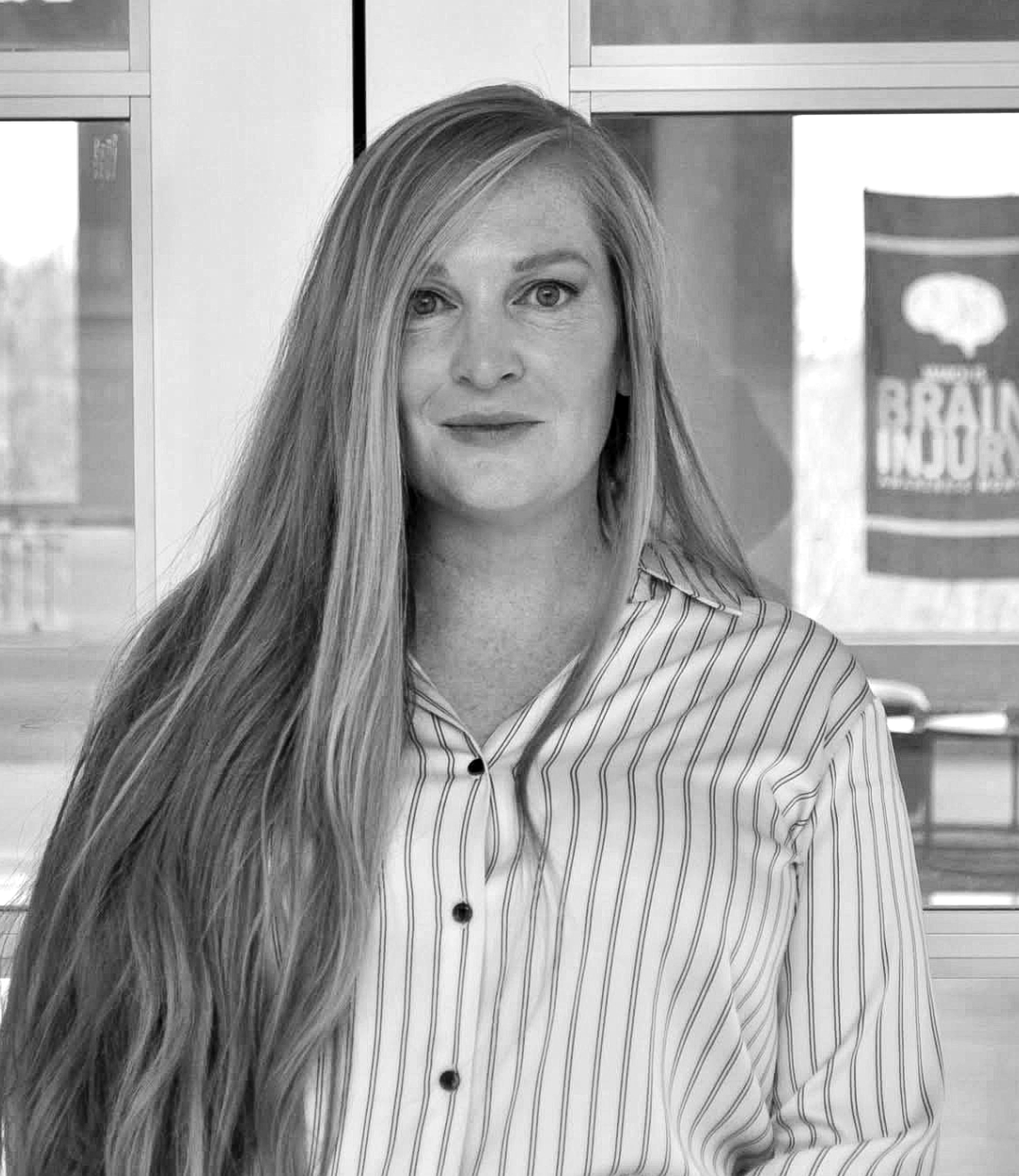 A black and white photo of a woman with long hair wearing a striped shirt.