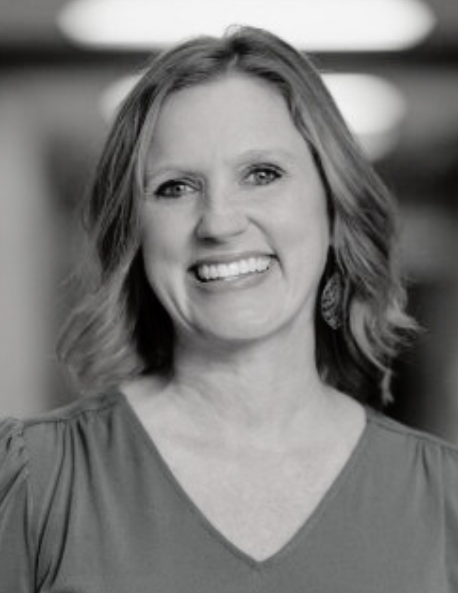 Jennifer Daniel. A black and white photo of a woman wearing a necklace and smiling.