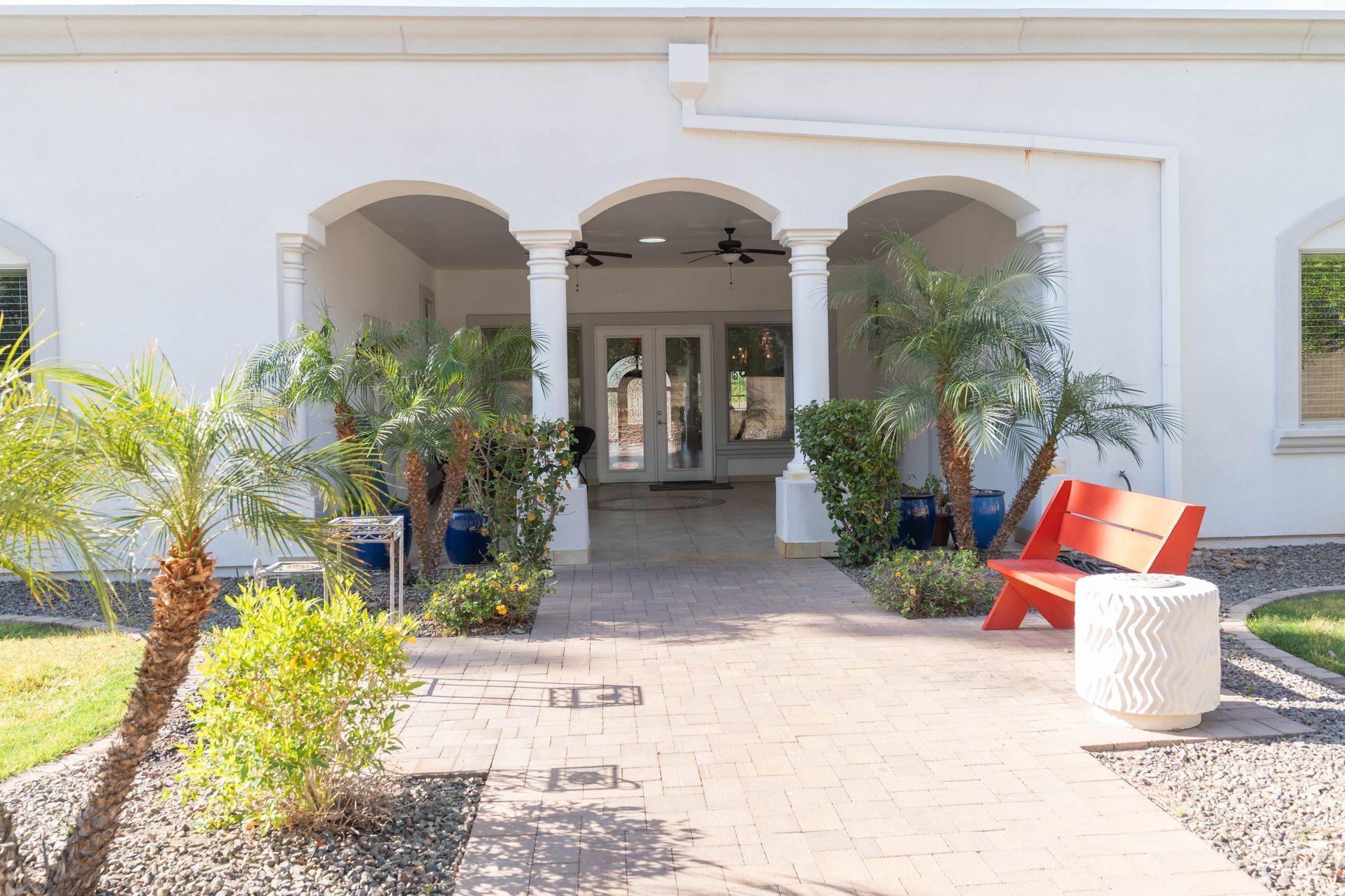 A white house with a red bench in front of it.