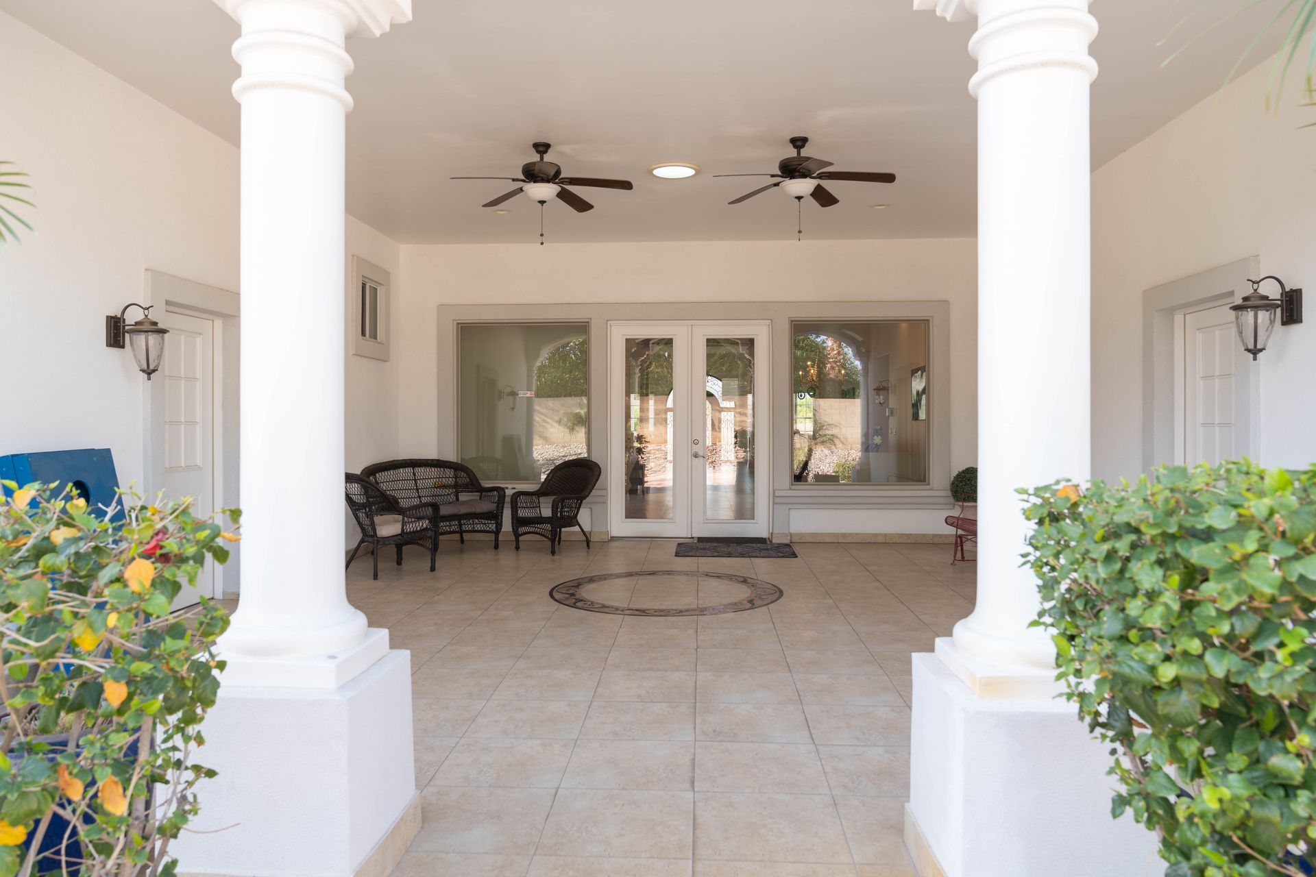 A white house with a patio and a ceiling fan.