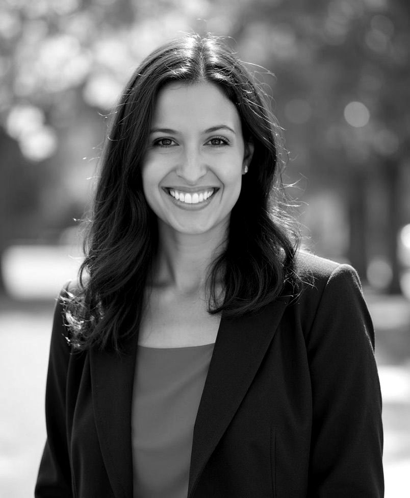 Dr. Devon Turnbull. A black and white photo of a woman wearing a jacket and smiling.