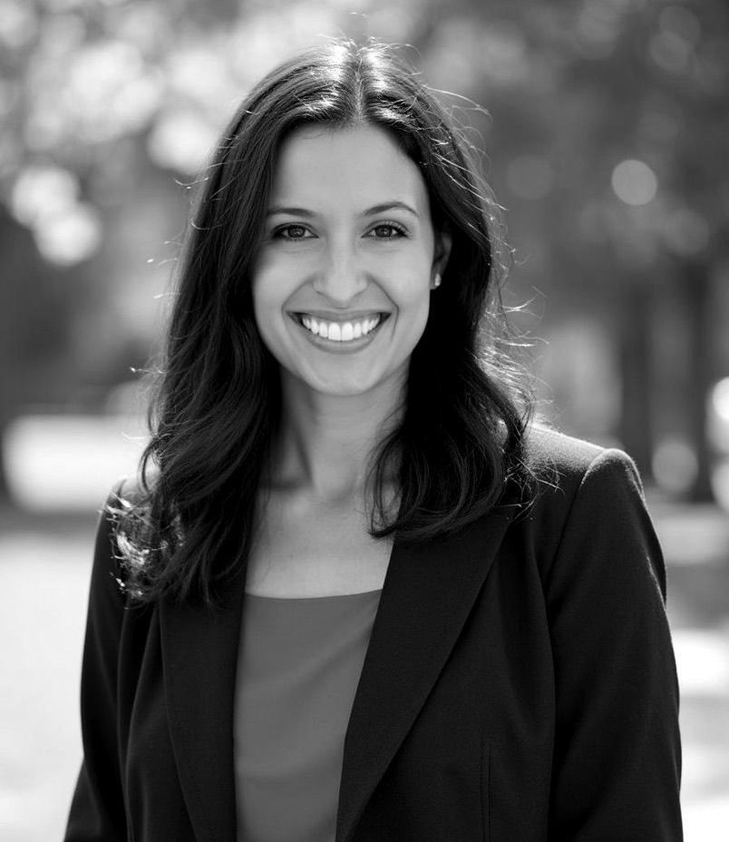 A black and white photo of a woman in a suit smiling.