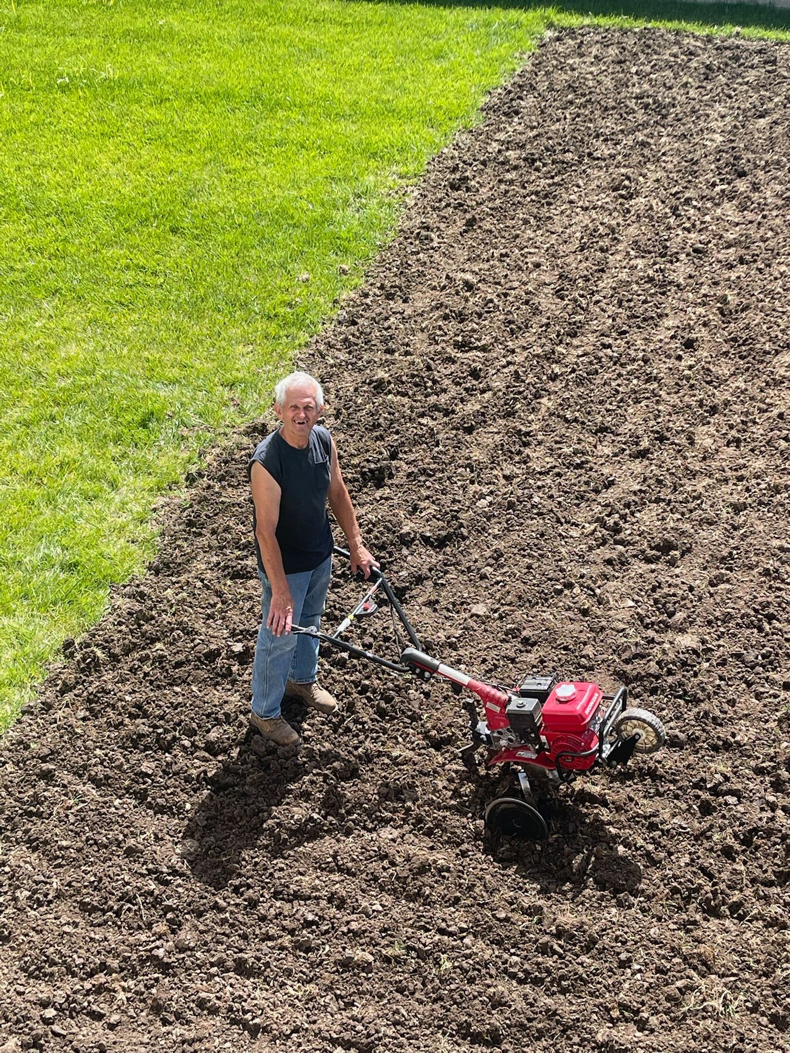 A man is plowing a field with a tiller.