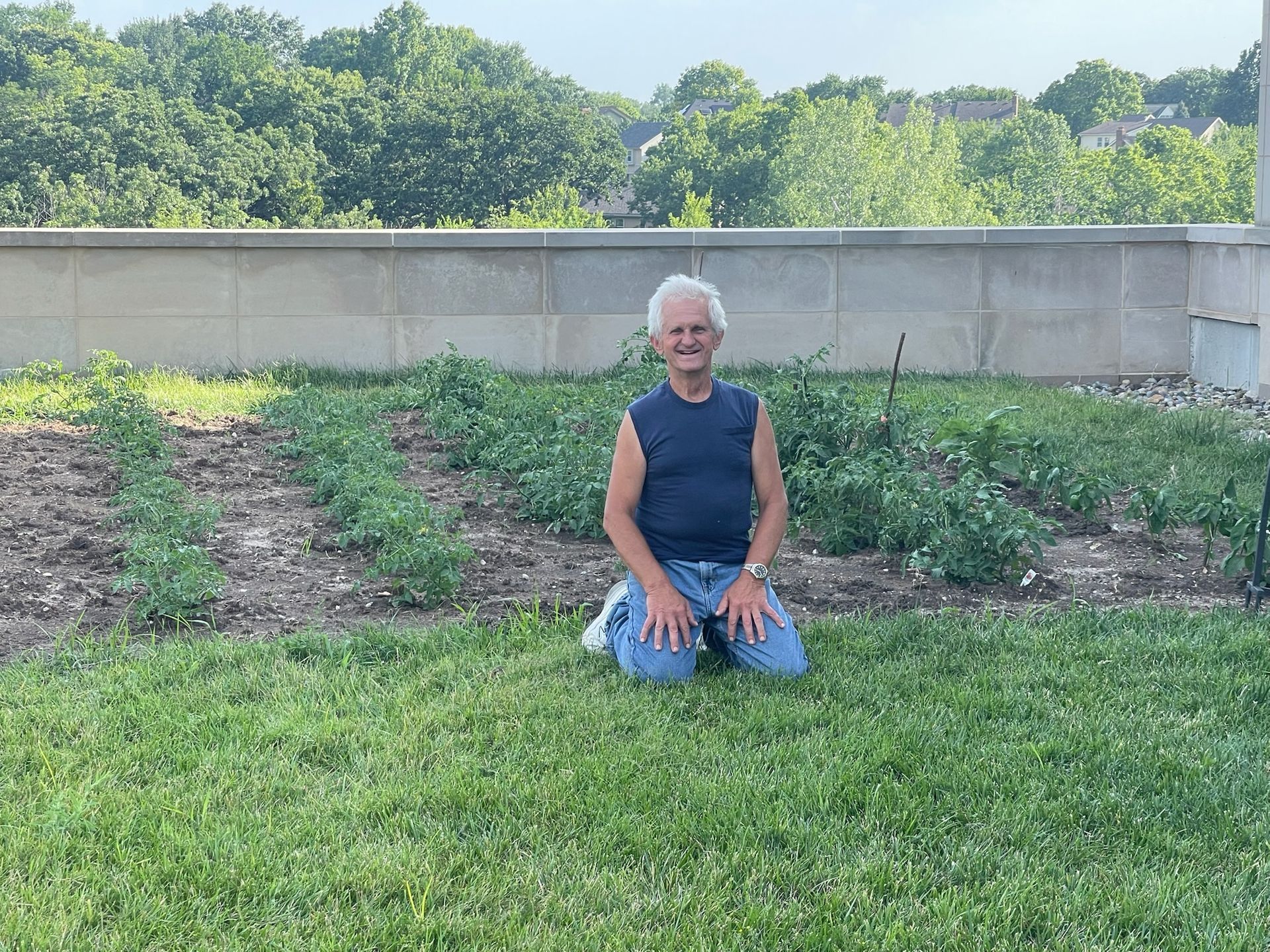 A man is kneeling down in a field of grass.