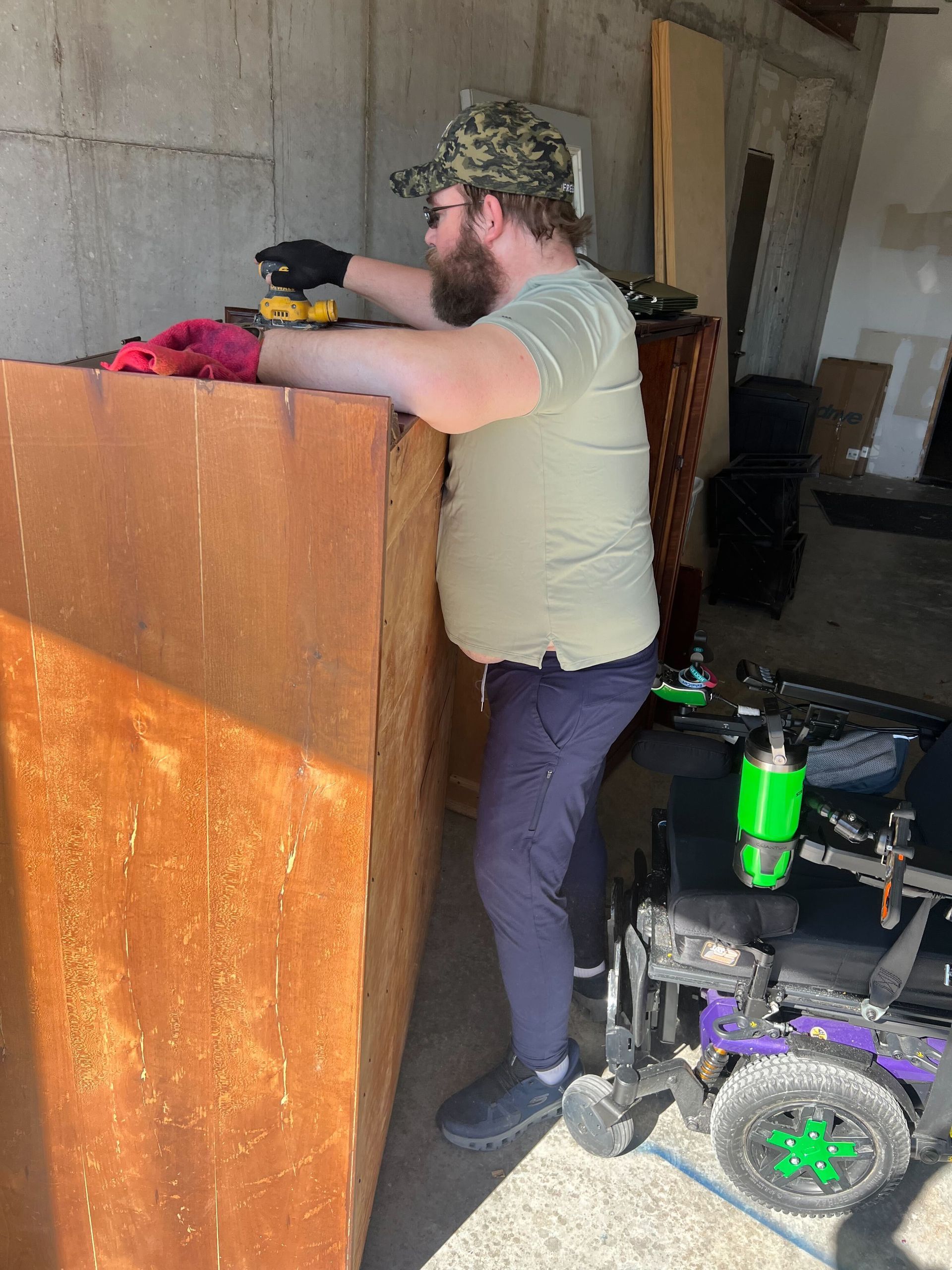 A man in a wheelchair is working on a piece of wood.
