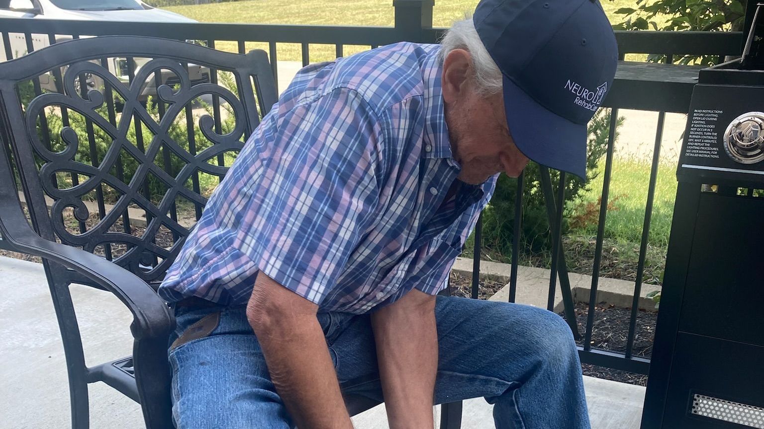 A man is sitting on a bench wearing a baseball cap.