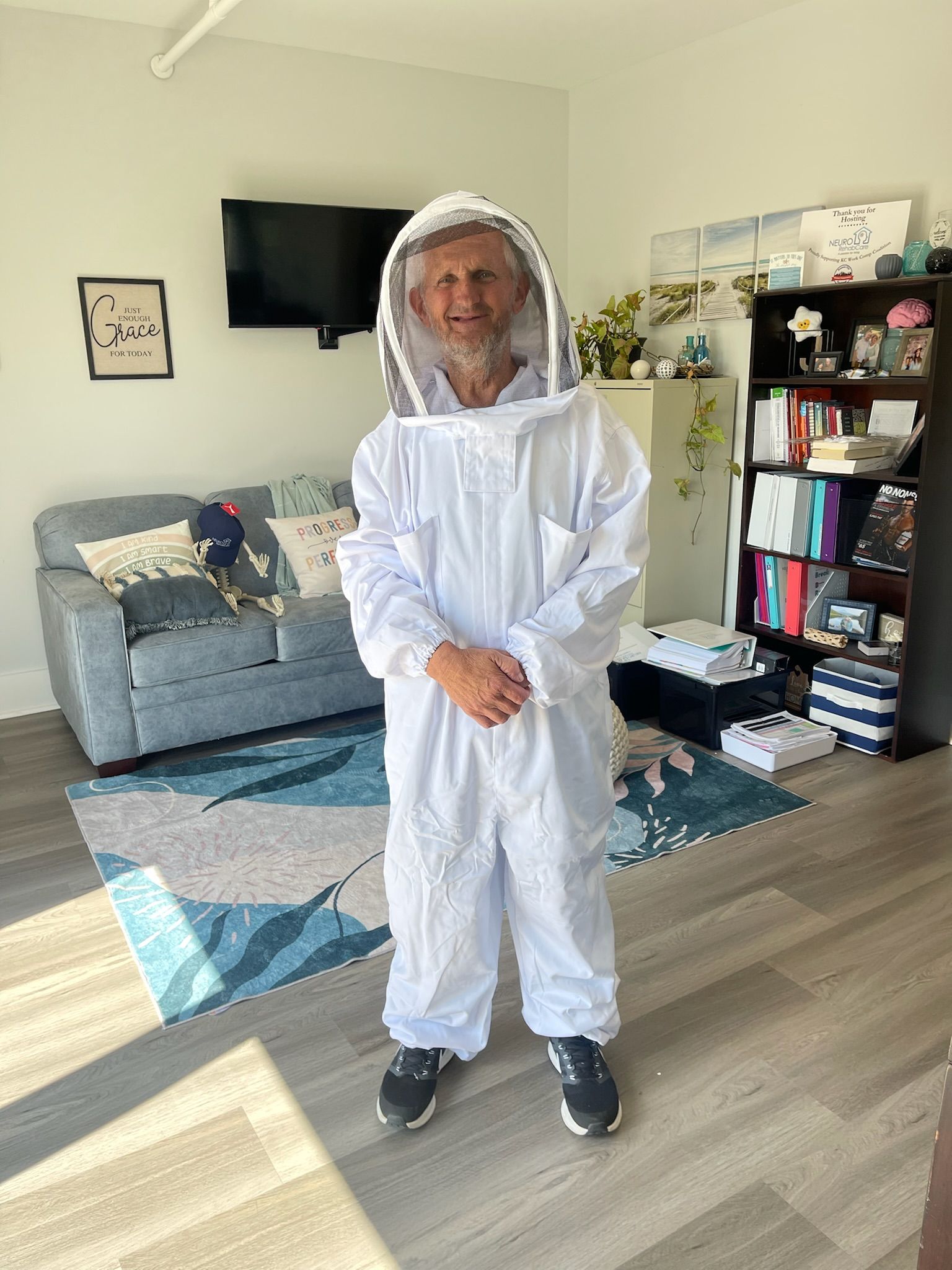 A man in a bee suit is standing in a living room.