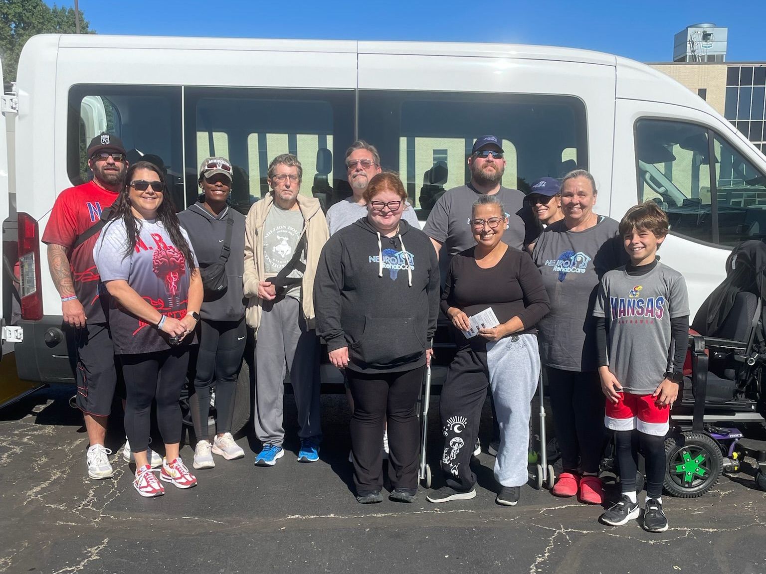 A group of people are posing for a picture in front of a van.