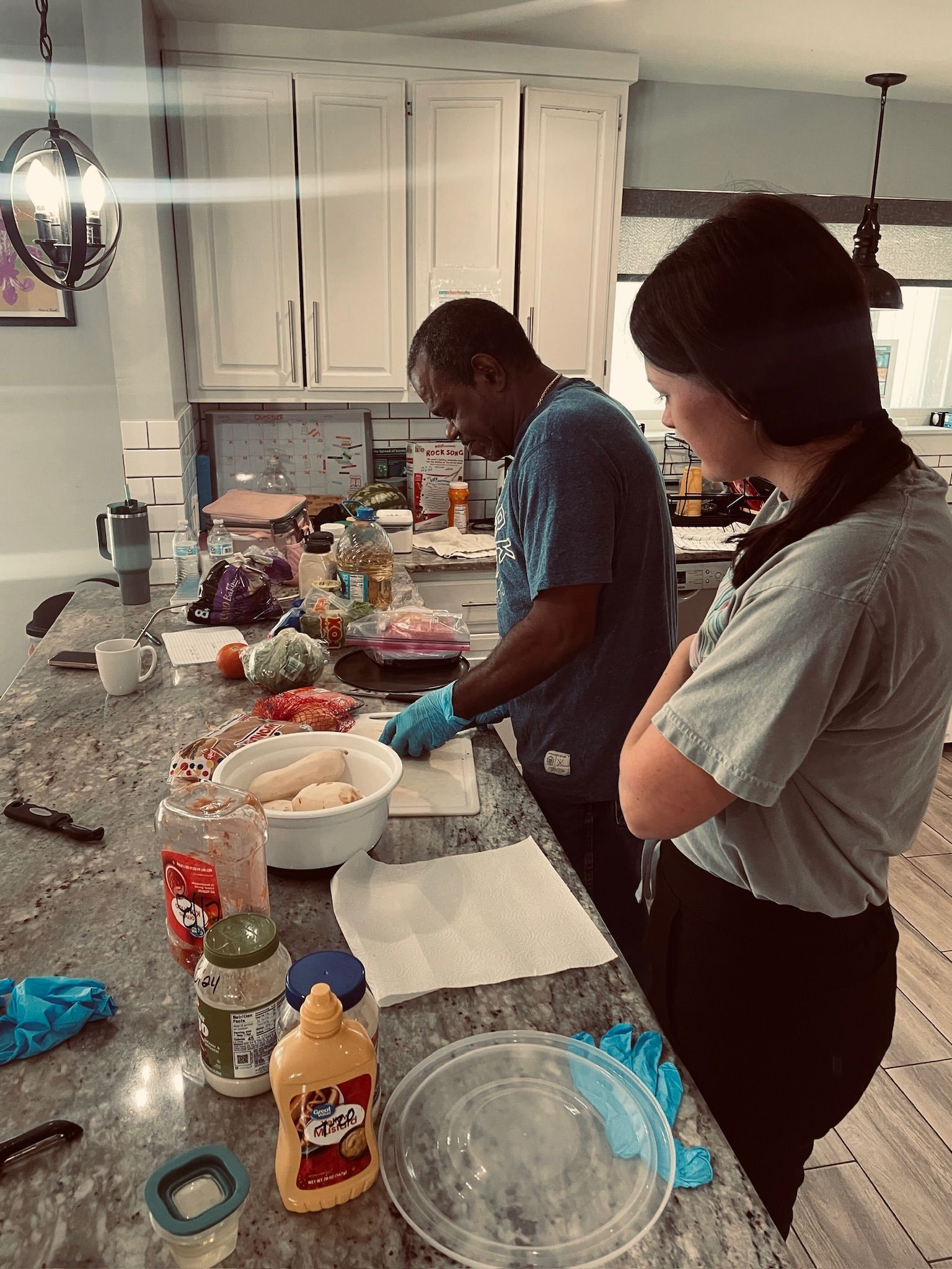 A man and a woman are standing at a kitchen counter preparing food.