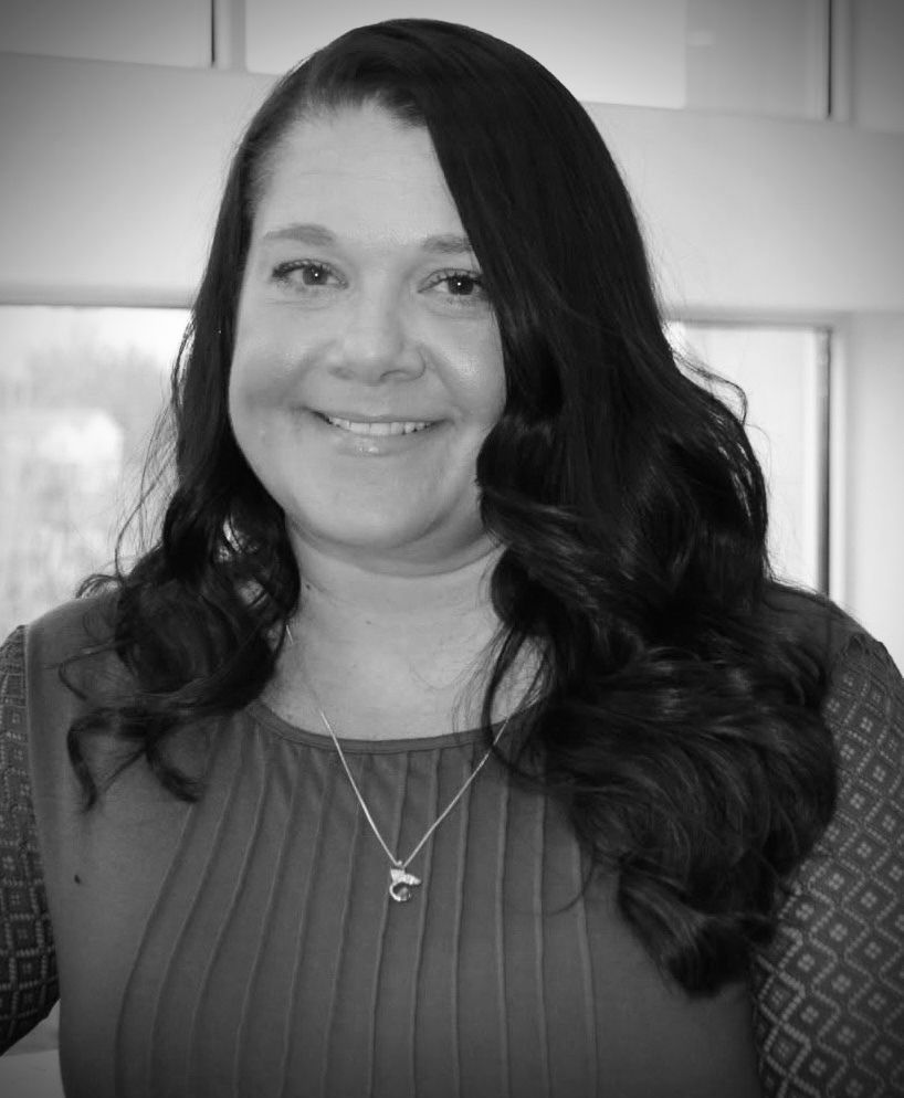 A black and white photo of a woman wearing a necklace and smiling.
