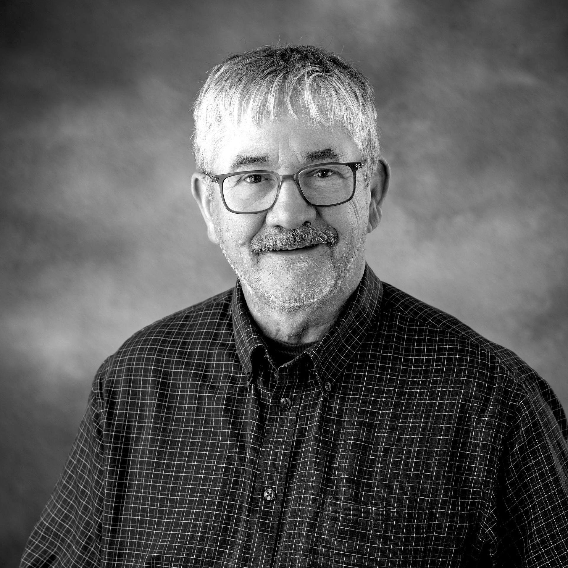 A black and white photo of a man with glasses and a beard.