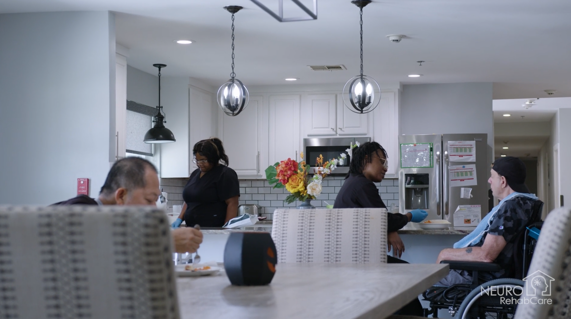A group of people are sitting at a table in a kitchen.