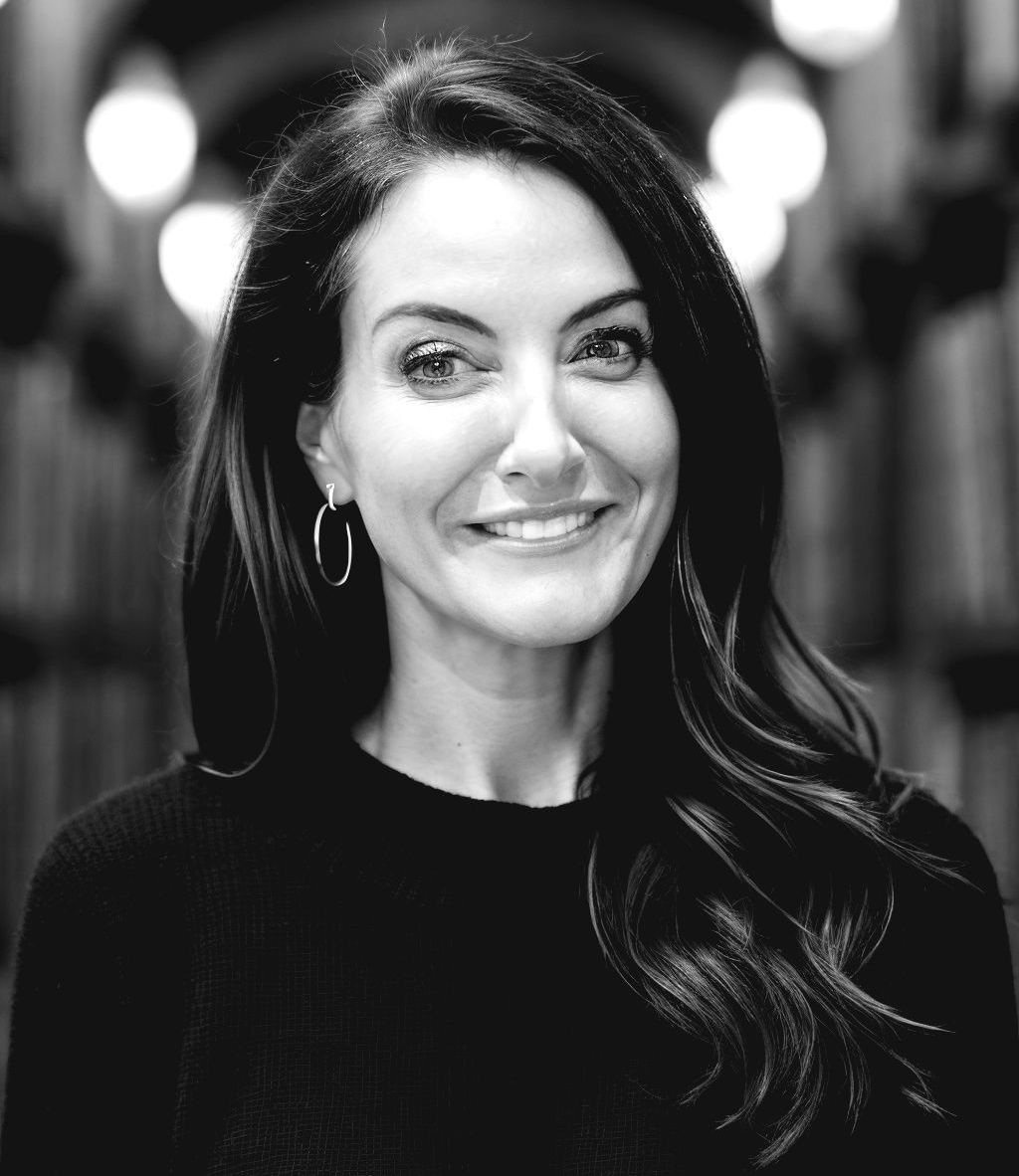 A black and white photo of a smiling woman wearing hoop earrings.