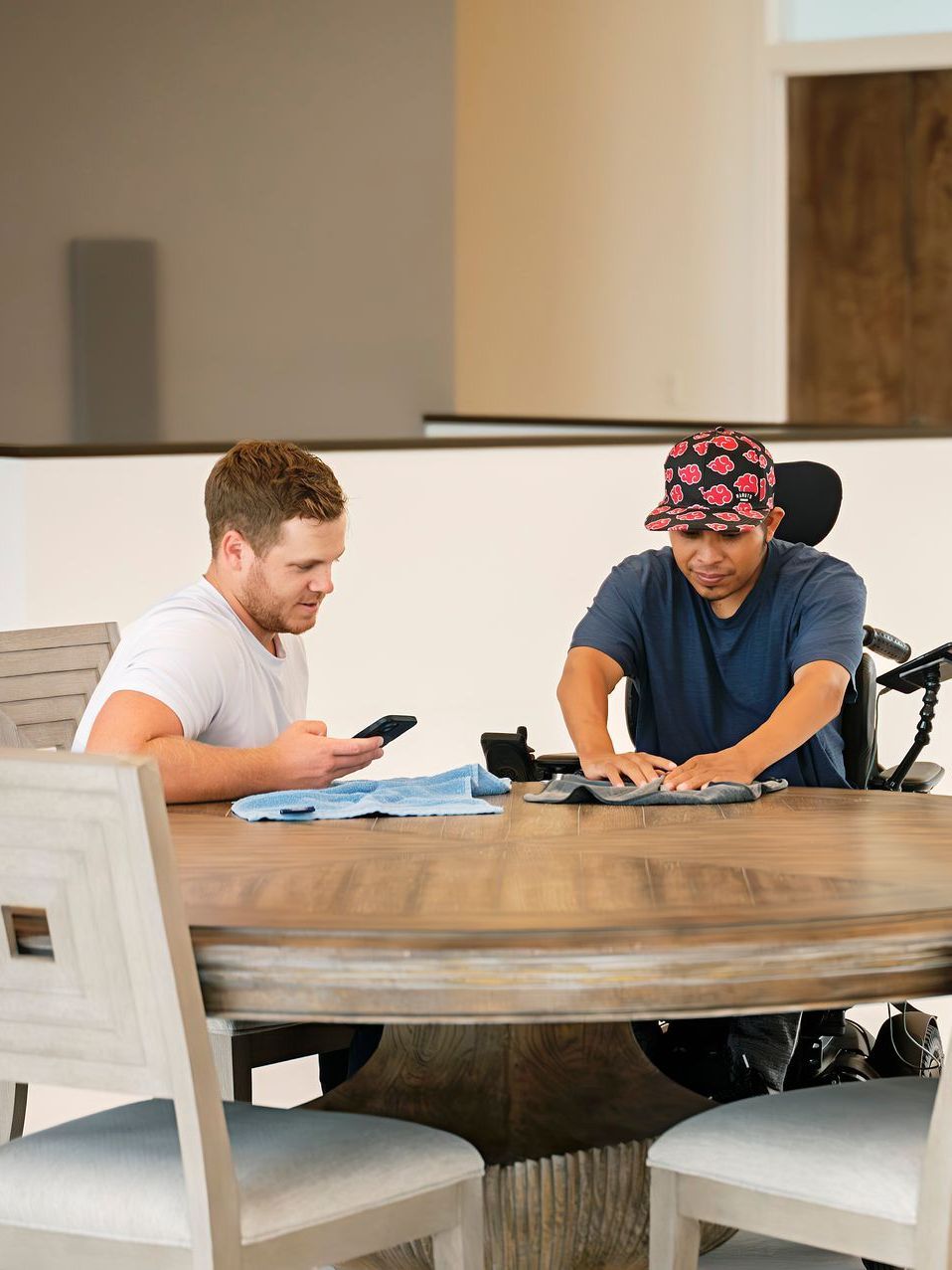 A man in a wheelchair is sitting at a table with another man.