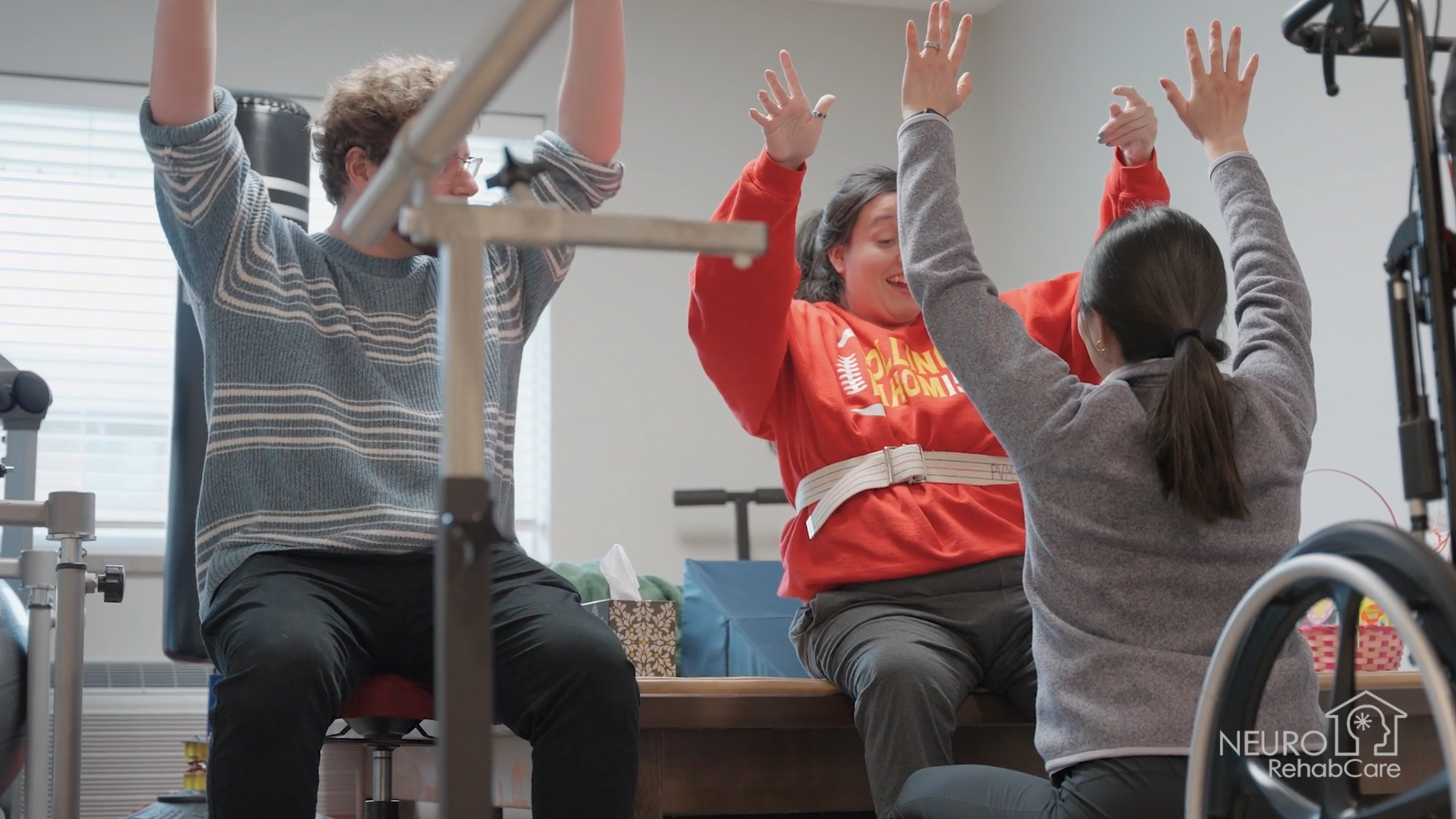 A man and a woman are sitting on a table with their arms in the air.