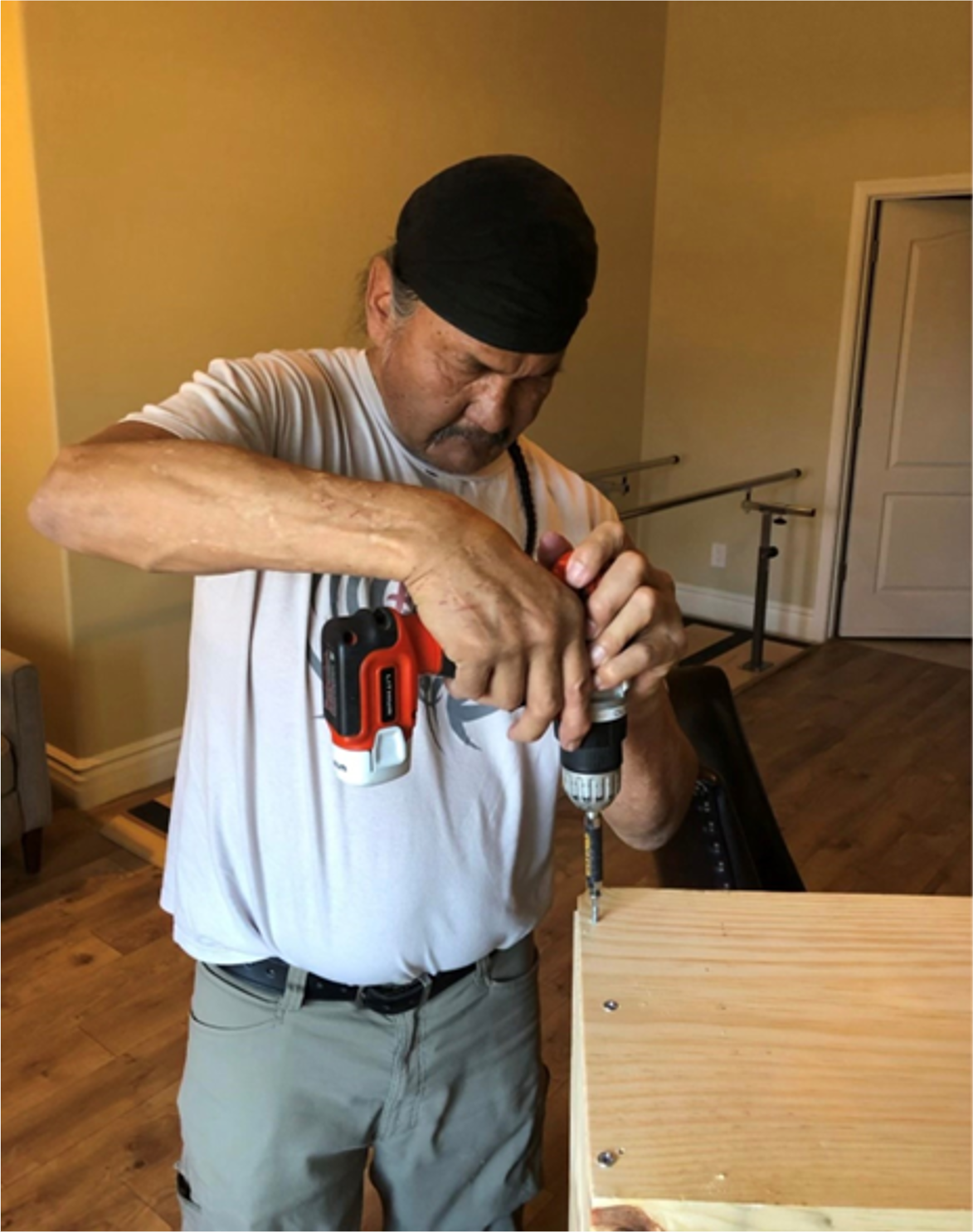 A man is working on a piece of wood with a drill.