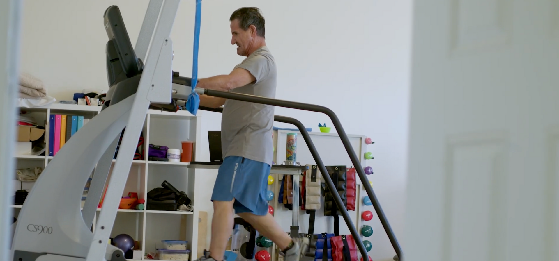 A man is standing on a treadmill in a room.