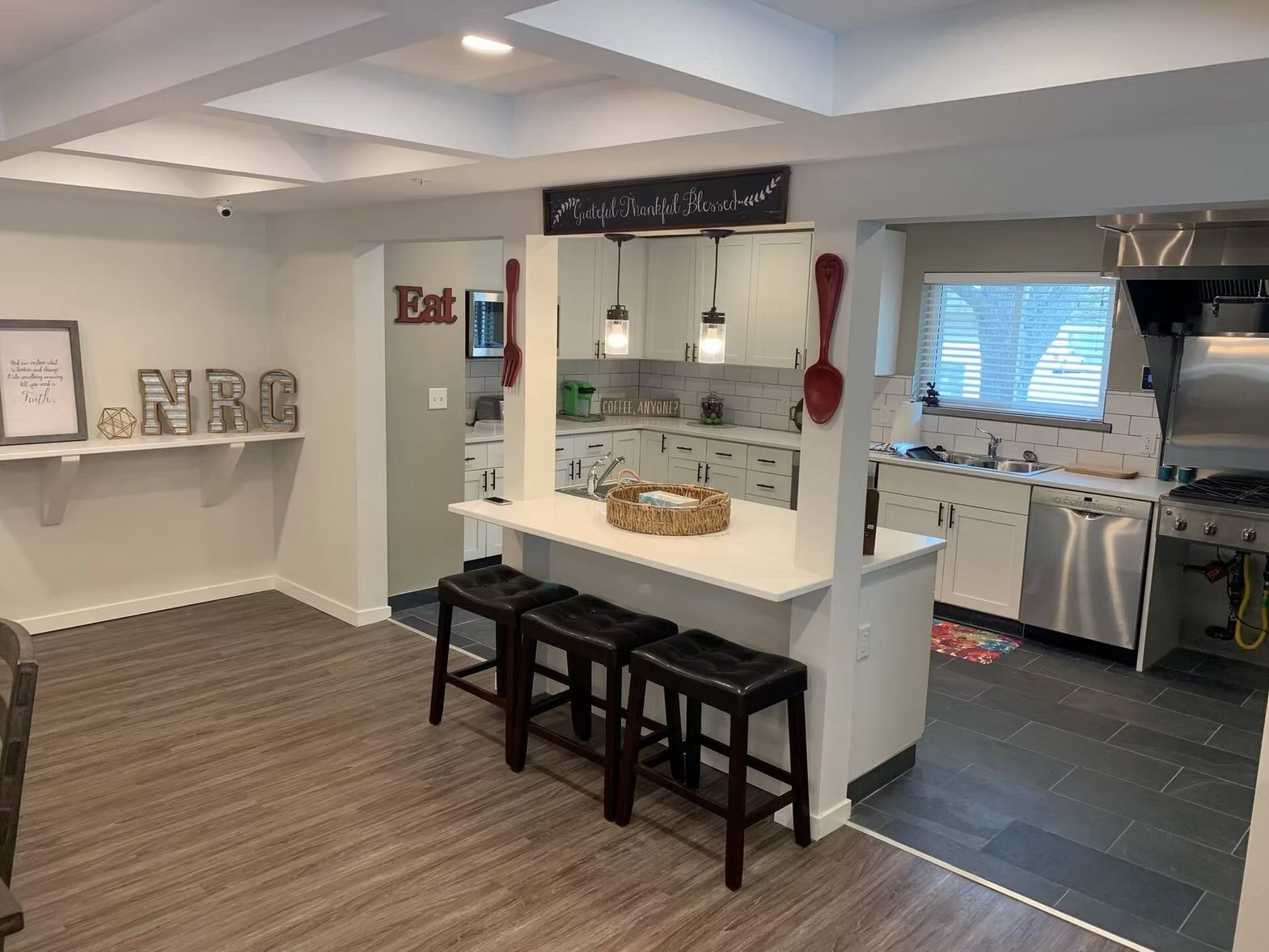A kitchen with a large island and stools and a stove.