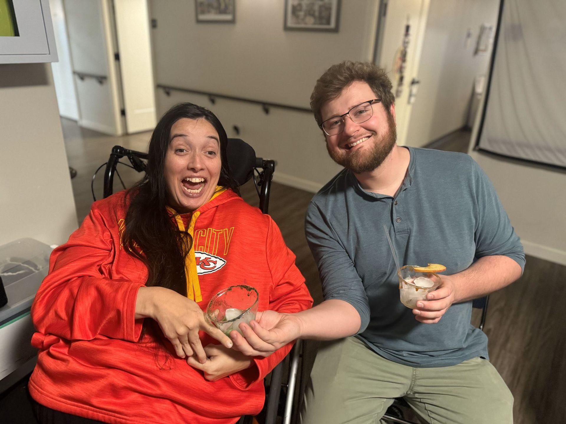 A woman in a wheelchair is sitting next to a man in a blue shirt.